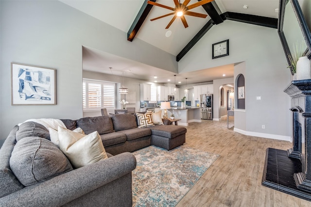 1912 Sunny Side Dr, Little Elm, TX 75068 - living room with a fireplace, light wood-type flooring, a ceiling fan, beamed ceiling, and arched walkways