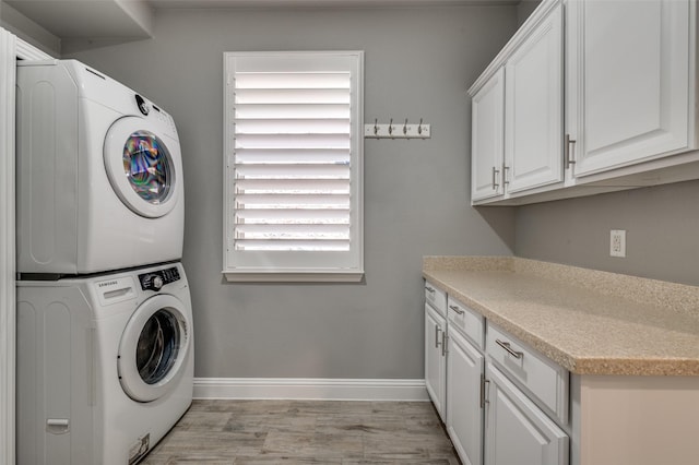1912 Sunny Side Dr, Little Elm, TX 75068 - washroom with estacked washer and dryer, baseboards, light wood-style floors, and cabinet space
