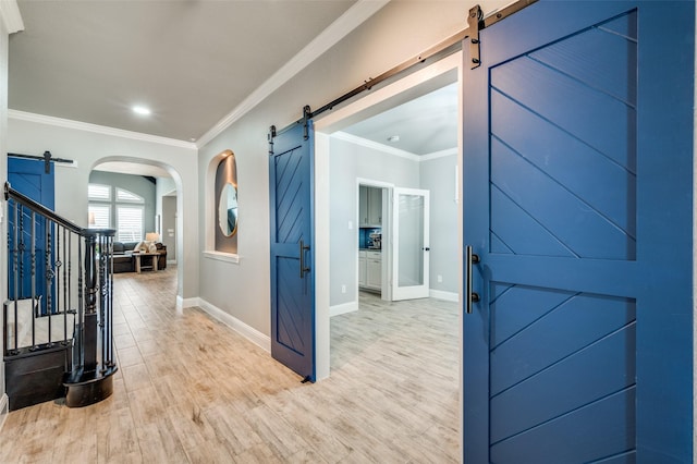 1912 Sunny Side Dr, Little Elm, TX 75068 - foyer with a barn door, ornamental molding, baseboards, light wood finished floors, and arched walkways