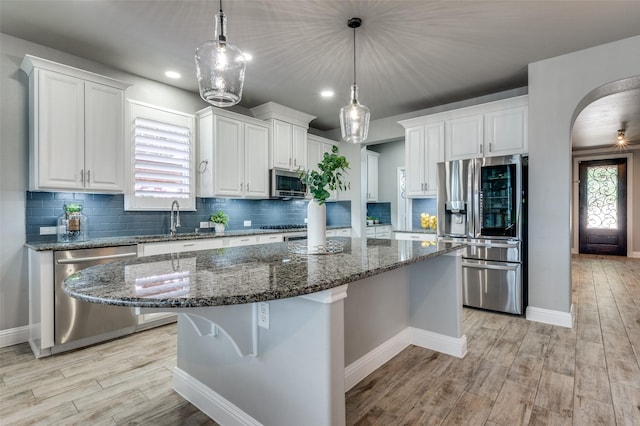 1912 Sunny Side Dr, Little Elm, TX 75068 - kitchen with stainless steel appliances, a sink, light wood-style floors, a kitchen island, and white cabinetry