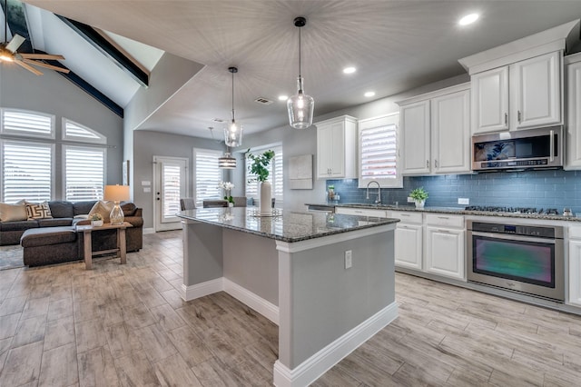 1912 Sunny Side Dr, Little Elm, TX 75068 - kitchen with stainless steel appliances, light wood finished floors, stone countertops, a center island, and recessed lighting