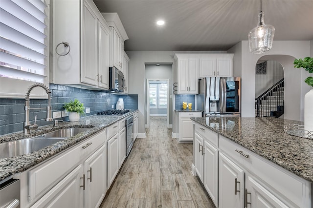 1912 Sunny Side Dr, Little Elm, TX 75068 - kitchen featuring stainless steel appliances, a sink, white cabinetry, arched walkways, and recessed lighting