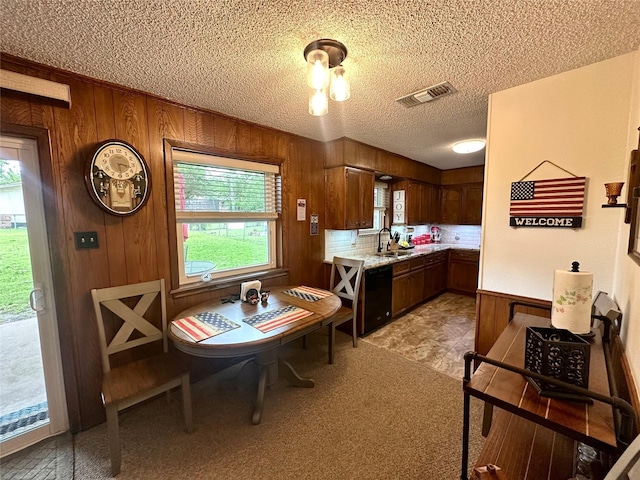 922 S Valentine Dr, Sherman, TX 75090 - kitchen with dishwasher, a sink, light countertops, wood walls, and a textured ceiling