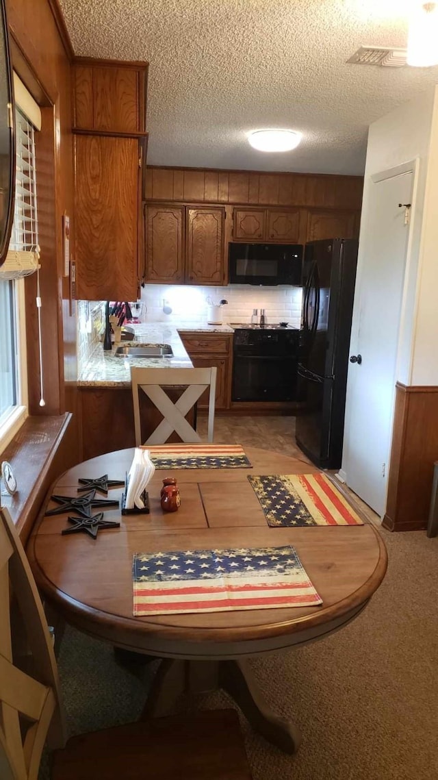 922 S Valentine Dr, Sherman, TX 75090 - kitchen featuring black appliances, brown cabinetry, a textured ceiling, light countertops, and a sink