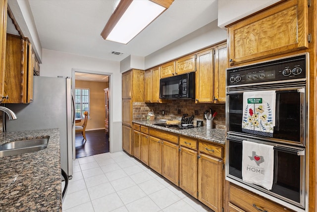 7108 Stonybrooke Dr, North Richland Hills, TX 76182 - kitchen with black appliances, a sink, decorative backsplash, light tile patterned floors, and brown cabinetry