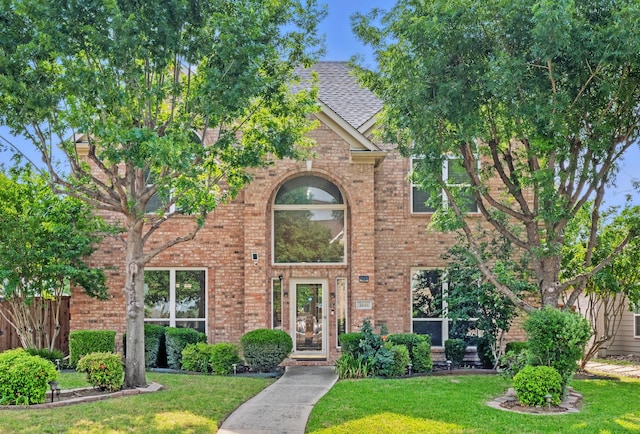 traditional-style house featuring brick siding and a shingled roof