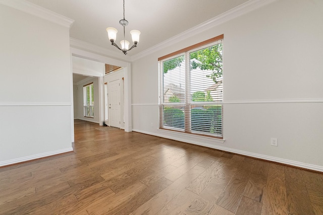 unfurnished room with a chandelier, crown molding, plenty of natural light, baseboards, and wood finished floors