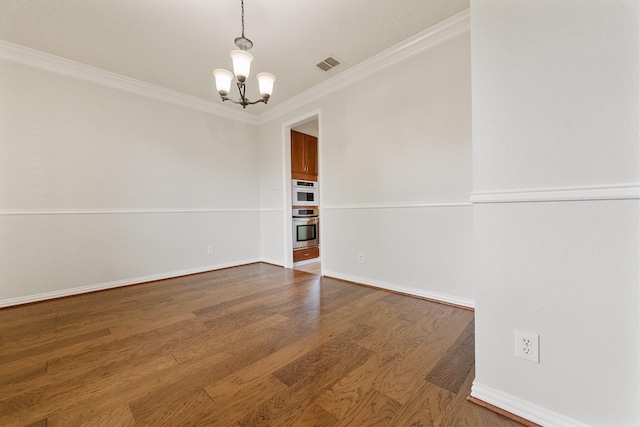 spare room featuring a chandelier, ornamental molding, wood finished floors, and baseboards