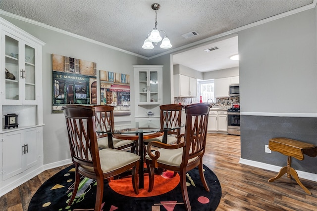 2614 Ivandell Ave, Dallas, TX 75211 - dining space with a chandelier, a textured ceiling, wood finished floors, crown molding, and baseboards