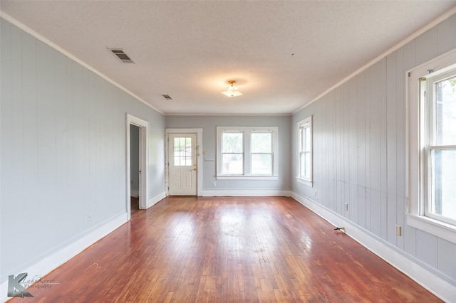 1810 Merchant St, Abilene, TX 79603 - unfurnished room with ornamental molding, hardwood / wood-style floors, baseboards, a textured ceiling, and wood walls