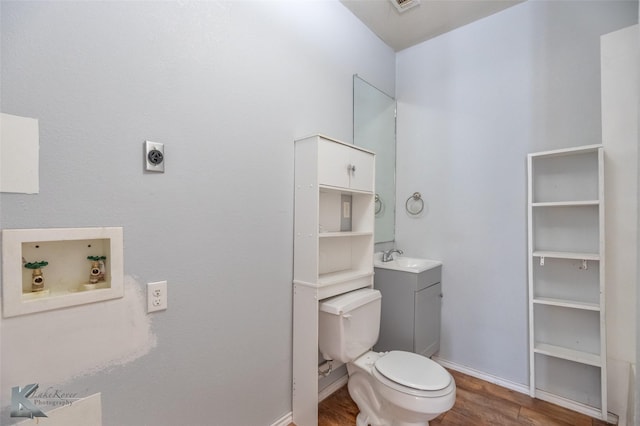 1810 Merchant St, Abilene, TX 79603 - bathroom featuring wood finished floors, toilet, baseboards, and vanity