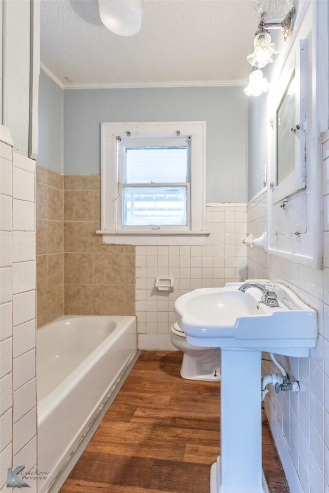 1810 Merchant St, Abilene, TX 79603 - full bath featuring crown molding, wood finished floors, tile walls, a tub, and toilet