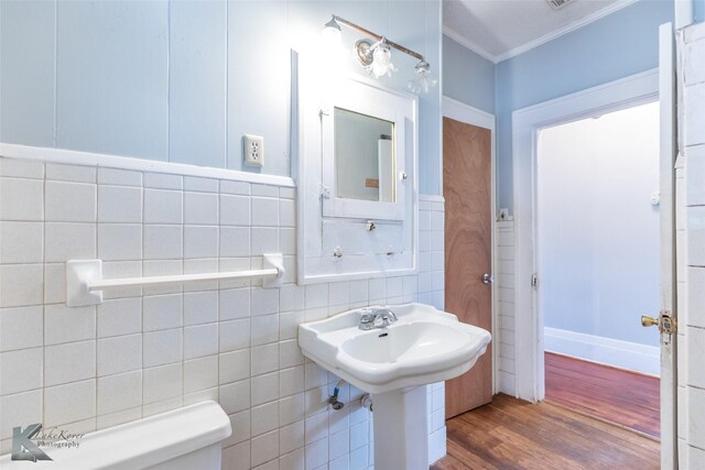 1810 Merchant St, Abilene, TX 79603 - half bath featuring ornamental molding, wood finished floors, tile walls, and toilet