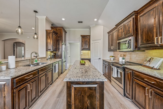 437 Sagebrush Dr, Aledo, TX 76008 - kitchen with appliances with stainless steel finishes, a sink, a kitchen island, crown molding, and arched walkways