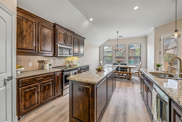 437 Sagebrush Dr, Aledo, TX 76008 - kitchen with stainless steel appliances, a sink, light wood-type flooring, dark brown cabinetry, and a center island