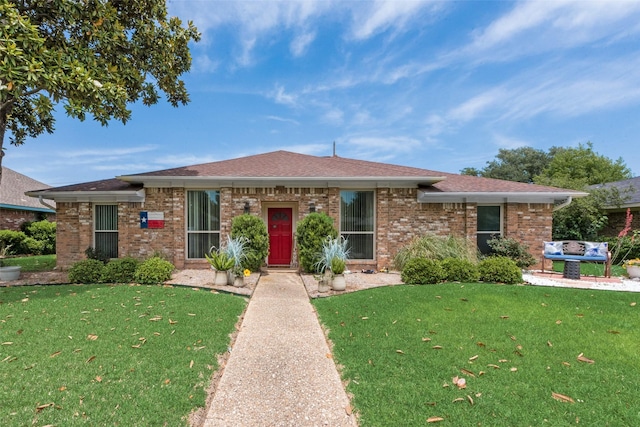 view of front facade with a front yard, brick siding, and a shingled roof
