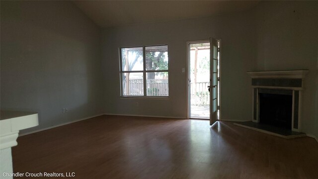 741 Cardinal Dr, Saginaw, TX 76131 - unfurnished living room featuring wood finished floors, a fireplace with raised hearth, lofted ceiling, and baseboards