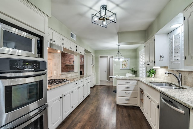 kitchen featuring appliances with stainless steel finishes, a sink, backsplash, and white cabinetry
