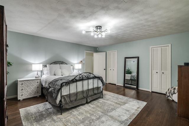 bedroom with a chandelier, multiple closets, wood finished floors, and baseboards