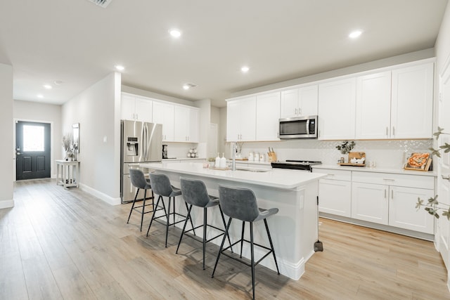 223 Quarry St, Melissa, TX 75454 - kitchen with stainless steel appliances, a kitchen bar, a kitchen island with sink, tasteful backsplash, and white cabinetry