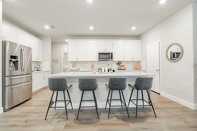 223 Quarry St, Melissa, TX 75454 - kitchen with stainless steel appliances, a sink, decorative backsplash, an island with sink, and white cabinetry