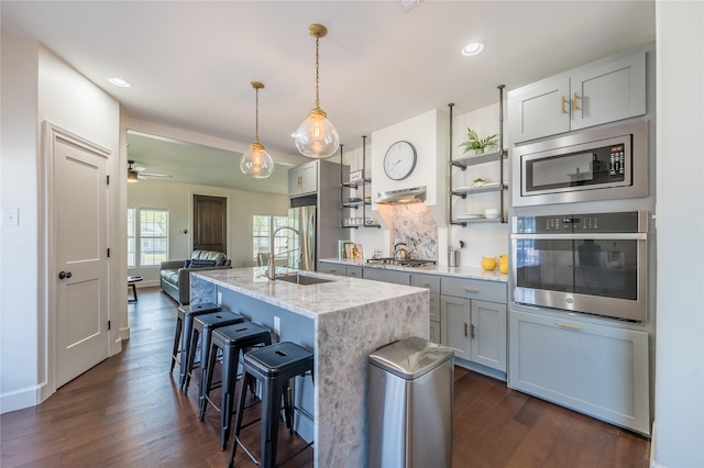 2025 Columbus Ave, Waco, TX 76701 - kitchen featuring stainless steel appliances, a sink, open shelves, a breakfast bar area, and dark wood finished floors