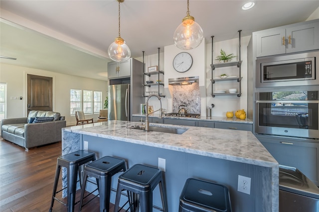 2025 Columbus Ave, Waco, TX 76701 - kitchen with appliances with stainless steel finishes, a sink, open shelves, a kitchen breakfast bar, and light stone counters
