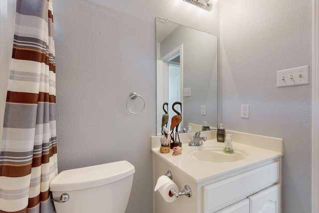 8614 Granville Dr, Dallas, TX 75249 - bathroom with vanity, toilet, a textured wall, and a shower with shower curtain