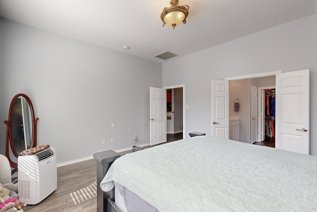 8614 Granville Dr, Dallas, TX 75249 - bedroom with wood finished floors, baseboards, and a walk in closet