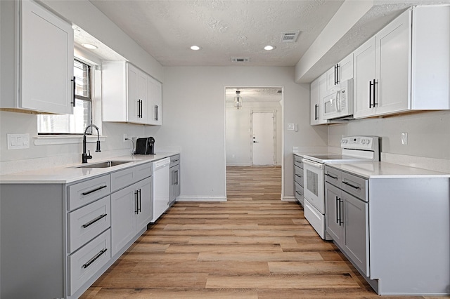 3229 Poteet Dr, Mesquite, TX 75150 - kitchen featuring white appliances, light countertops, light wood finished floors, a textured ceiling, and recessed lighting
