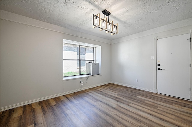 3229 Poteet Dr, Mesquite, TX 75150 - spare room featuring a chandelier, wood finished floors, and a textured ceiling
