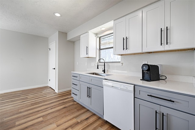 3229 Poteet Dr, Mesquite, TX 75150 - kitchen with white dishwasher, light wood-style floors, a textured ceiling, light countertops, and gray cabinetry