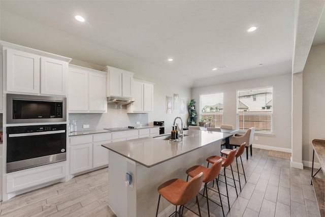 6005 Loving Ct, Midlothian, TX 76065 - kitchen with stainless steel oven, built in microwave, under cabinet range hood, a sink, and wood tiled floors