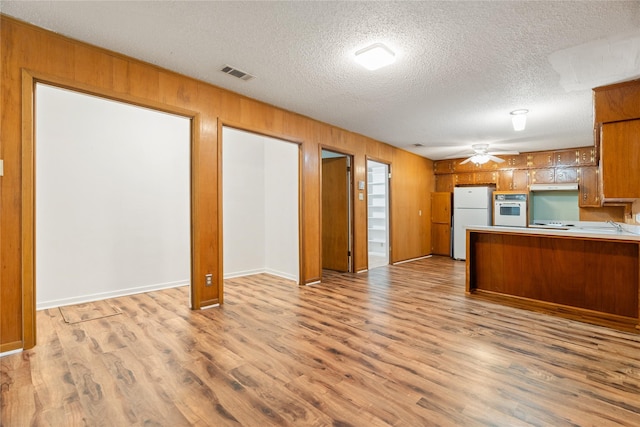 1019 E Elm St, Hillsboro, TX 76645 - kitchen with white appliances, ceiling fan, light wood-style flooring, a textured ceiling, and brown cabinetry