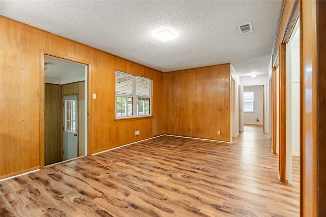 1019 E Elm St, Hillsboro, TX 76645 - unfurnished room with wood finished floors, a textured ceiling, and wooden walls