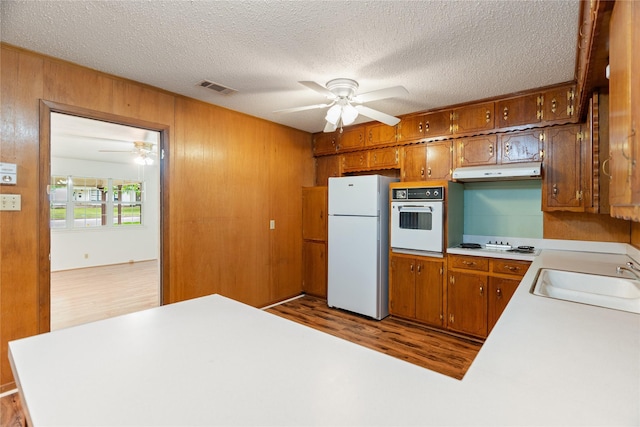 1019 E Elm St, Hillsboro, TX 76645 - kitchen featuring white appliances, a sink, a ceiling fan, under cabinet range hood, and wooden walls