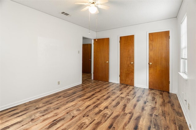 1019 E Elm St, Hillsboro, TX 76645 - unfurnished bedroom with wood finished floors, two closets, a ceiling fan, and baseboards