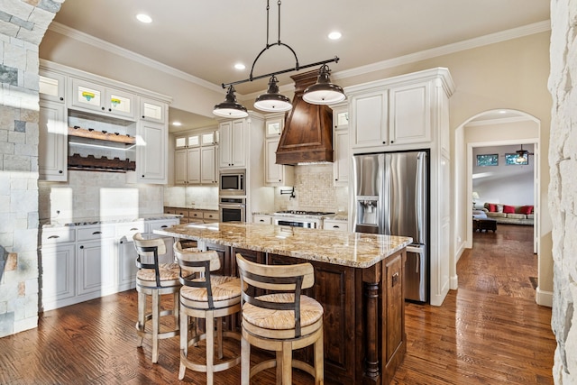 1100 Triple Crown Ct, Bartonville, TX 76226 - kitchen featuring stainless steel appliances, crown molding, custom range hood, a center island, and arched walkways
