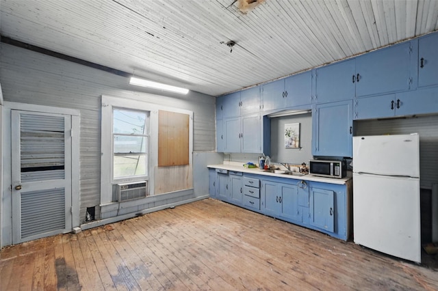 402 S Watson St, Alvarado, TX 76009 - kitchen with freestanding refrigerator, blue cabinetry, stainless steel microwave, light countertops, and light wood finished floors