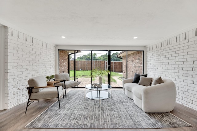 living room with brick wall, wood finished floors, and recessed lighting