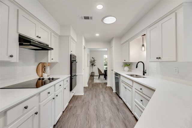 kitchen with a sink, under cabinet range hood, black appliances, white cabinets, and recessed lighting