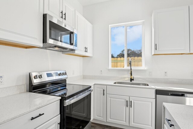 3613 Durango Trl, Granbury, TX 76048 - kitchen with stainless steel appliances, a sink, white cabinetry, and light stone countertops