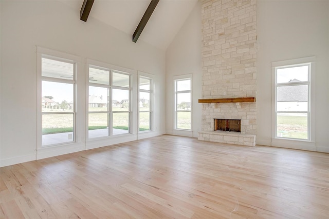 138 Buddy Ct, Millsap, TX 76066 - unfurnished living room with high vaulted ceiling, beam ceiling, light wood-type flooring, a stone fireplace, and baseboards