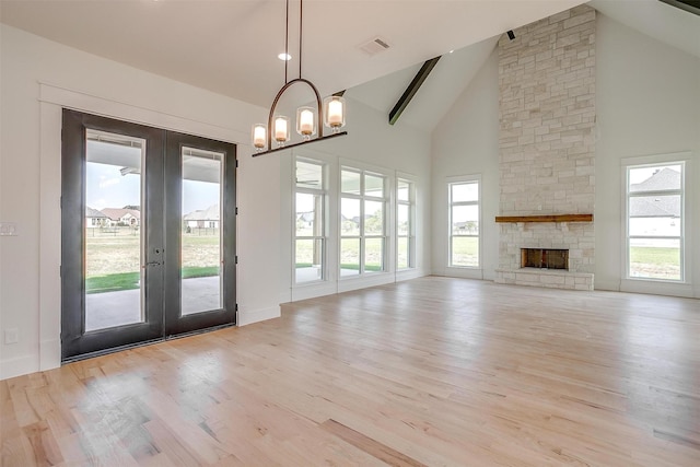 138 Buddy Ct, Millsap, TX 76066 - unfurnished living room featuring french doors, high vaulted ceiling, light wood-style floors, a chandelier, and a stone fireplace