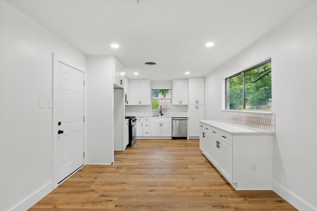 4709 Shady Hill Dr, Forest Hill, TX 76119 - kitchen featuring stainless steel appliances, backsplash, light countertops, light wood finished floors, and white cabinets