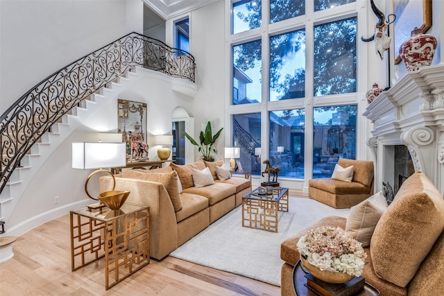 6616 Shoal Forest Ct, Plano, TX 75024 - living area featuring a high ceiling, stairs, wood finished floors, a glass covered fireplace, and baseboards