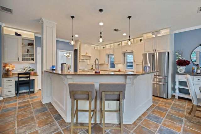 1123 Shadetree Ln, Allen, TX 75013 - kitchen featuring stainless steel fridge, tasteful backsplash, a kitchen breakfast bar, stone tile floors, and ornamental molding