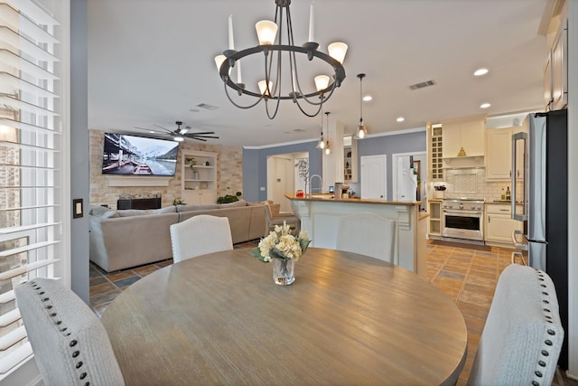 1123 Shadetree Ln, Allen, TX 75013 - dining room featuring a chandelier, a ceiling fan, crown molding, recessed lighting, and a fireplace