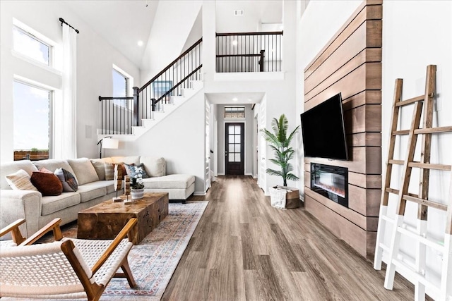 4342 Hudson St, Fate, TX 75087 - living area with wood finished floors, a towering ceiling, stairway, and a glass covered fireplace