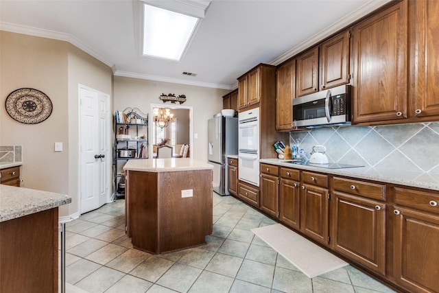 2420 Norwich Dr, Carrollton, TX 75006 - kitchen with appliances with stainless steel finishes, a center island, light tile patterned floors, decorative backsplash, and crown molding